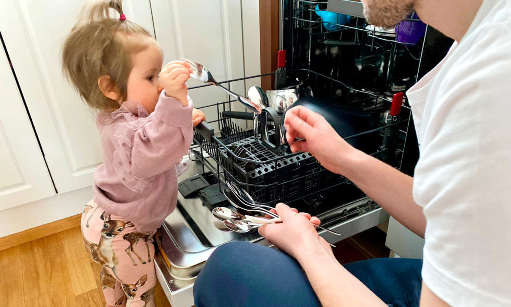 Olivia auttaa isää tyhjentämään tiskikonetta. 