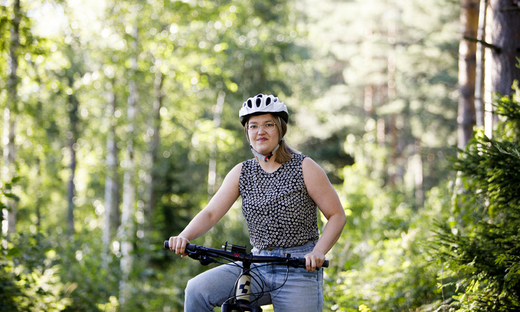 Johanna maastopyöräilee metsässä. 