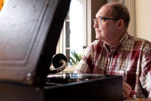 I förgrunden syns en gammal grammofon. Jyrki sitter i bakgrunden.