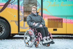 Riikka istuu sähköpyörätuolissa ulkona.