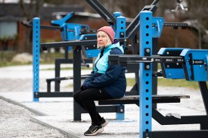 Tuula istuu ulkona kuntoilulaitteella.