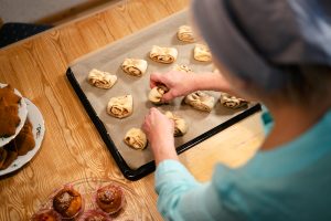 Tuula asettelee leipomiaan korvapuusteja pellille.