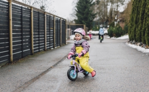 På gården är det fart och fläng när Lotta åker sparkcykel och Peetu susar förbi med sin cykel.