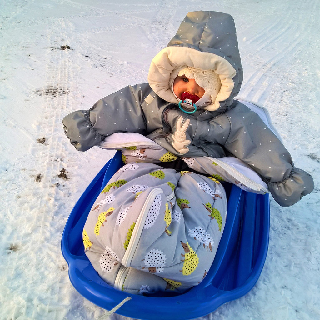 Säde, 1 år, sitter i pulkan.