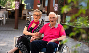 : Marja ja Arto Ahti istuvat hoivakodin kesäisellä pihalla.