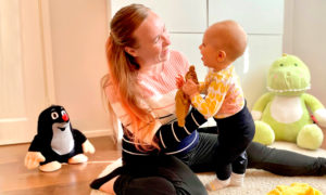Jenni sitter på golvet och leker med minstingen som snart fyller ett år.