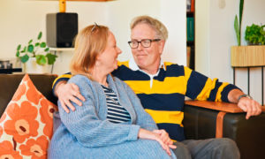 Heikki och Tuula sitter på soffan och tittar på varandra.