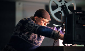 Seppo työstää filmiä filmiprojektorilla.