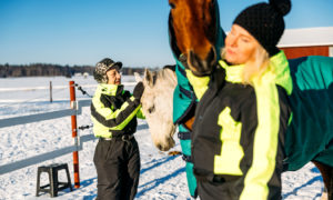 Aino ja Marika ovat ulkona hevosten kanssa.