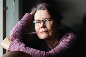 Rauni stöder sig mot handen och tittar framåt.