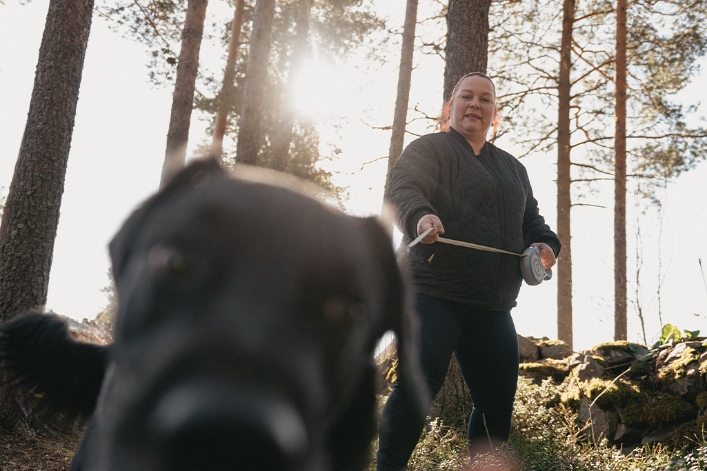 Hanne på promenad med sin hund. Hunden nosar på kameran.