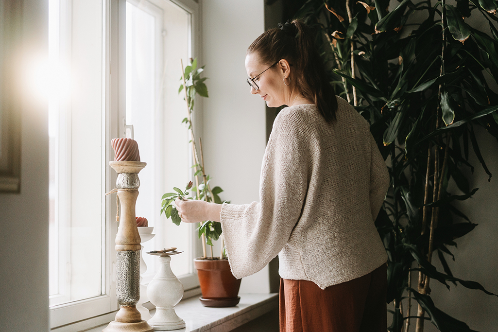 Katri beundrar en växt som snart börjar blomma på fönsterbrädan. 