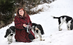 Anita Ojanen ulkona kolmen koiransa kanssa.
