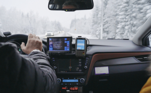 Kuva taksin sisältä. Taksi ajaa lumisessa maisemassa.
