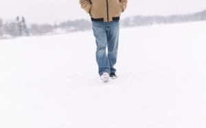 Mies kävelee lumimaisemassa.