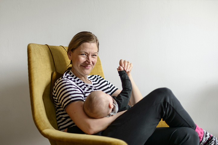 Merja Mähkä sitter i en fåtölj med babyn.