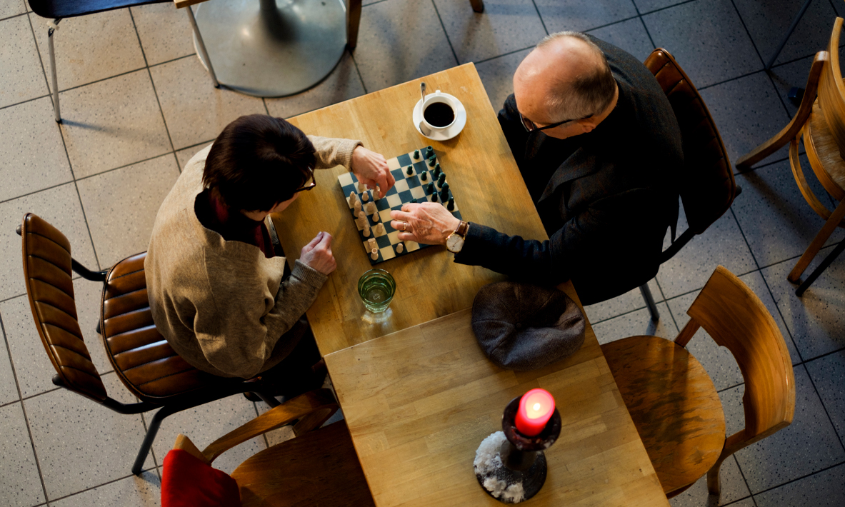 Kaksi iäkästä ihmistä pelaa shakkia.