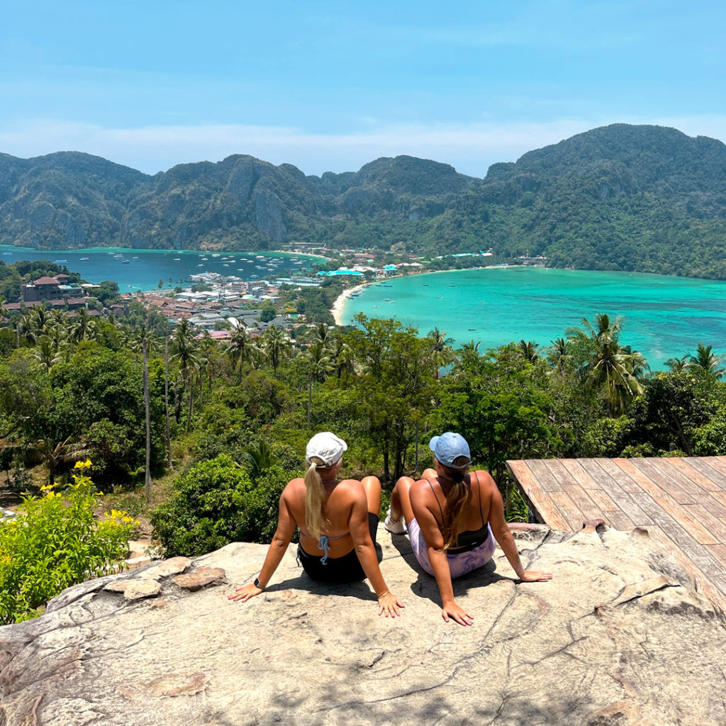 Elena ja Melisa ottavat aurinkoa kalliolla. Taustalla näkyy kaunista Thaimaan maisemaa.