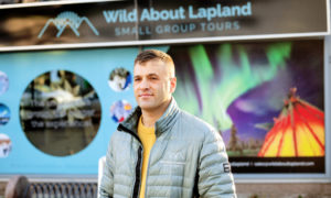 Theo Turner står framför fönstret vid sitt företag i Rovaniemi. På fönstret står texten Wild about Lapland.