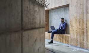 en foretagare sitter med en bärbar dator i knät.